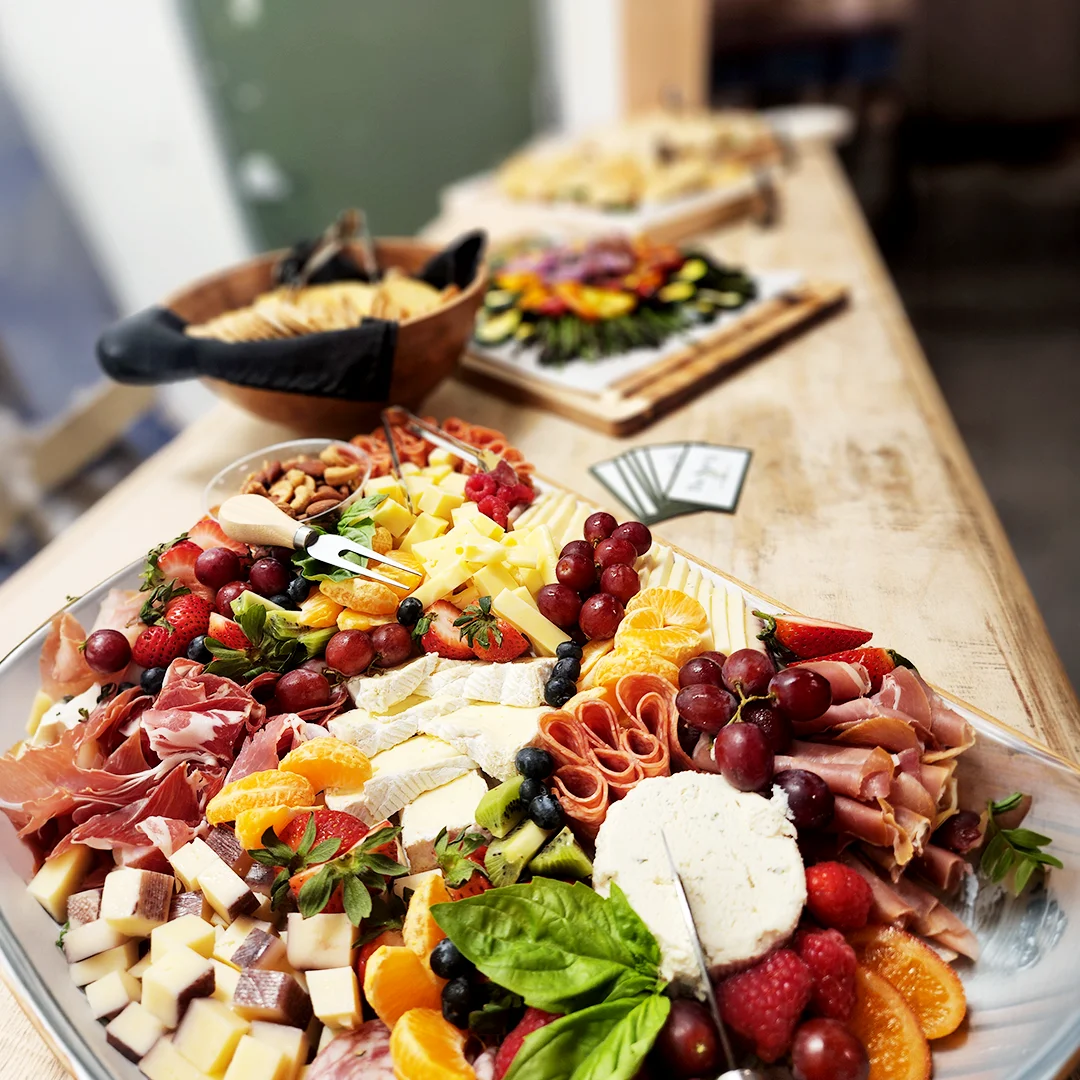 Grazing table featuring artisan cheeses, cured meats, fresh fruit, nuts, and charcuterie for a catered gathering.