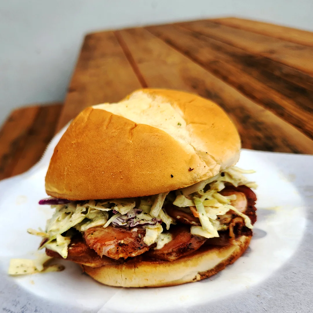 Smoked chicken sandwich topped with creamy coleslaw on a soft sandwich roll.